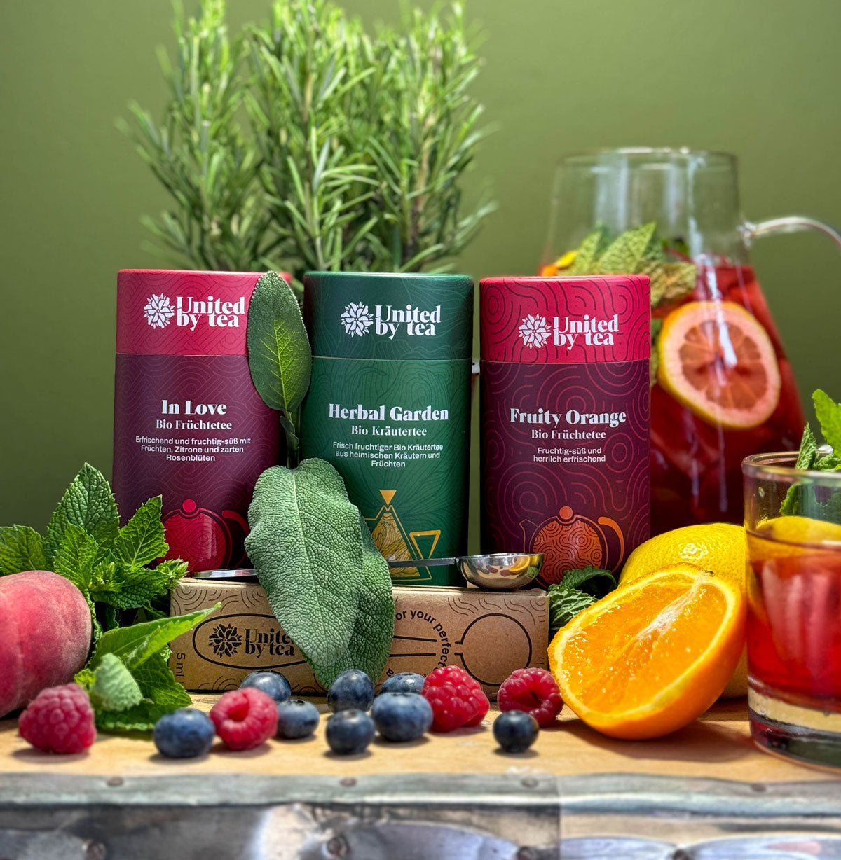 Bio-Tee-Dose mit Teemesslöffel in einem Beet aus Früchten