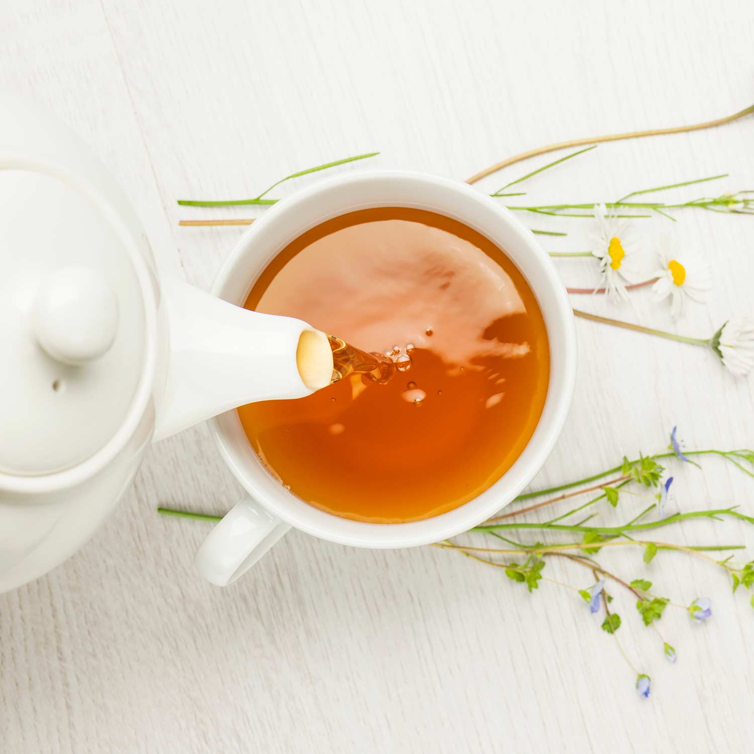 Rötlicher Tee wird in eine Tasse gegossen